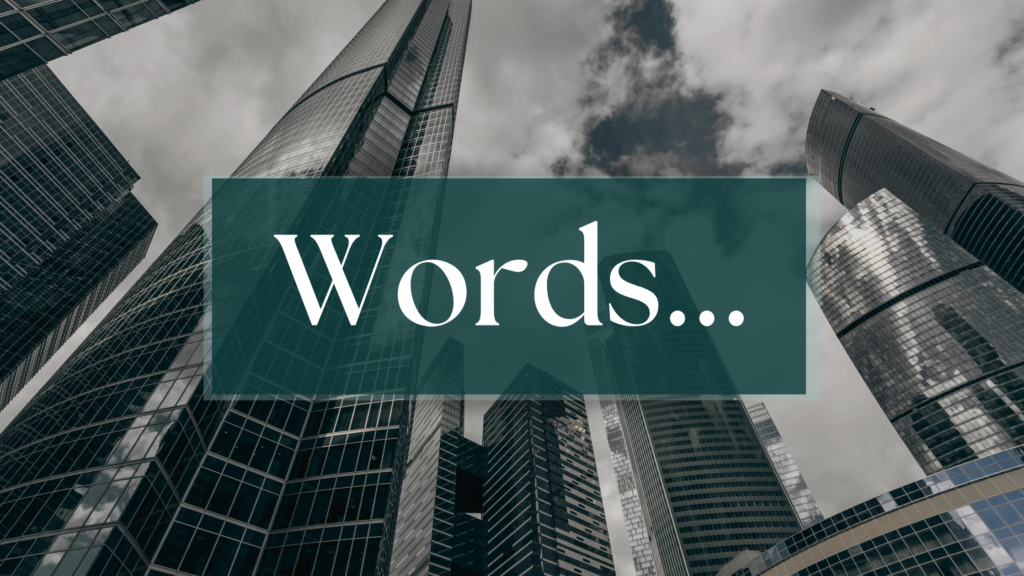 "Words..." in a blue rectangle with looming skyscrapers in the background in grayscale.